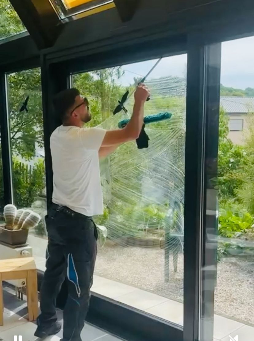 Mitarbeiter von FS Glas & Gebäudereinigung reinigt eine raumhohe Glastür mit dem Abzieher