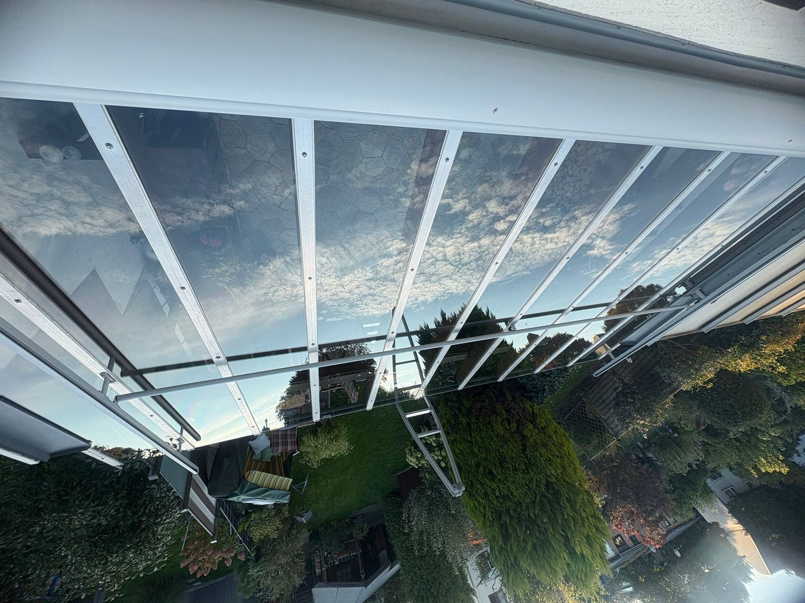 Gereinigtes Glasdach einer Terrassenüberdachung mit Blick in den Garten